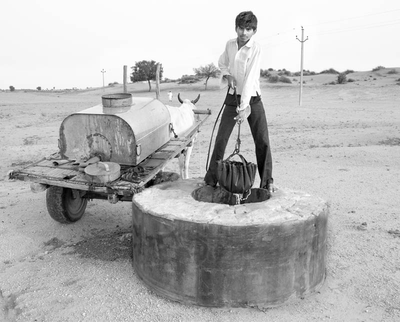 Children and Water - A teenager helping his family by collecting drinking water from a shallow well located outside the village in Bikaner district, Rajasthan